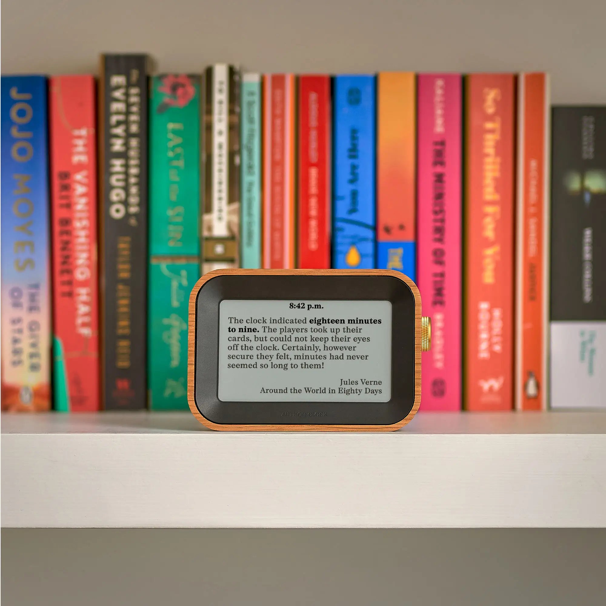 Author Clock Vol 1 Small on a bookshelf displaying a Jules Verne quote from Around the World in Eighty Days at 8:42 p.m., surrounded by colourful novels