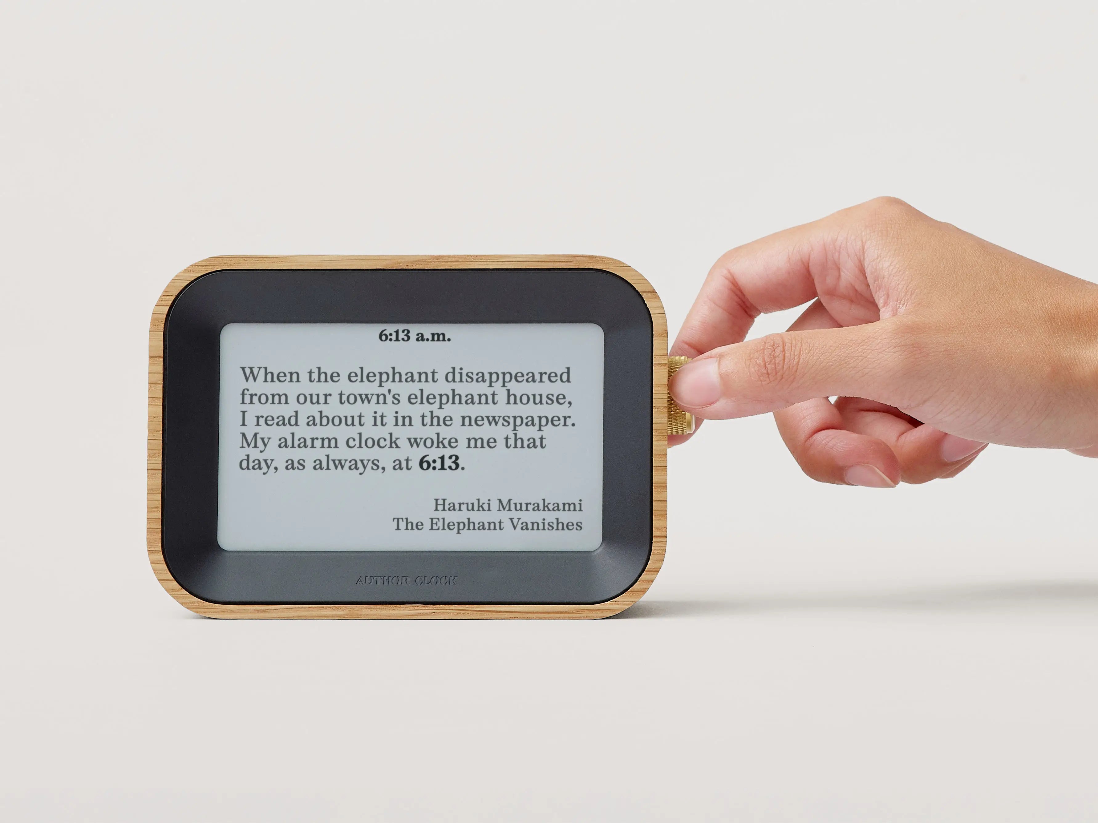 Author Clock showing a Haruki Murakami quote as a hand adjusts the brass crown