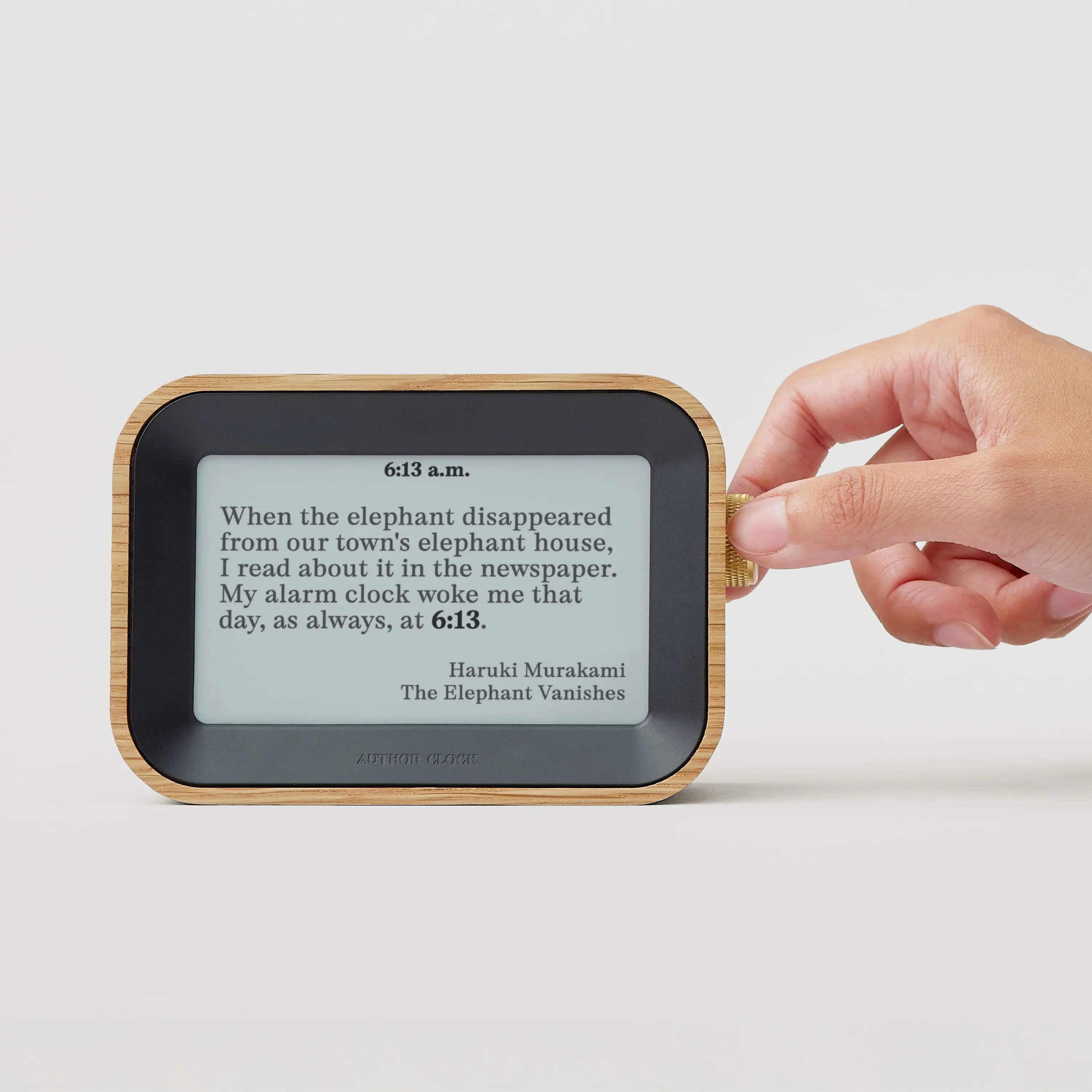 Author Clock Vol 1 Small showing a Haruki Murakami quote from The Elephant Vanishes at 6:13 a.m., with a hand turning the brass crown
